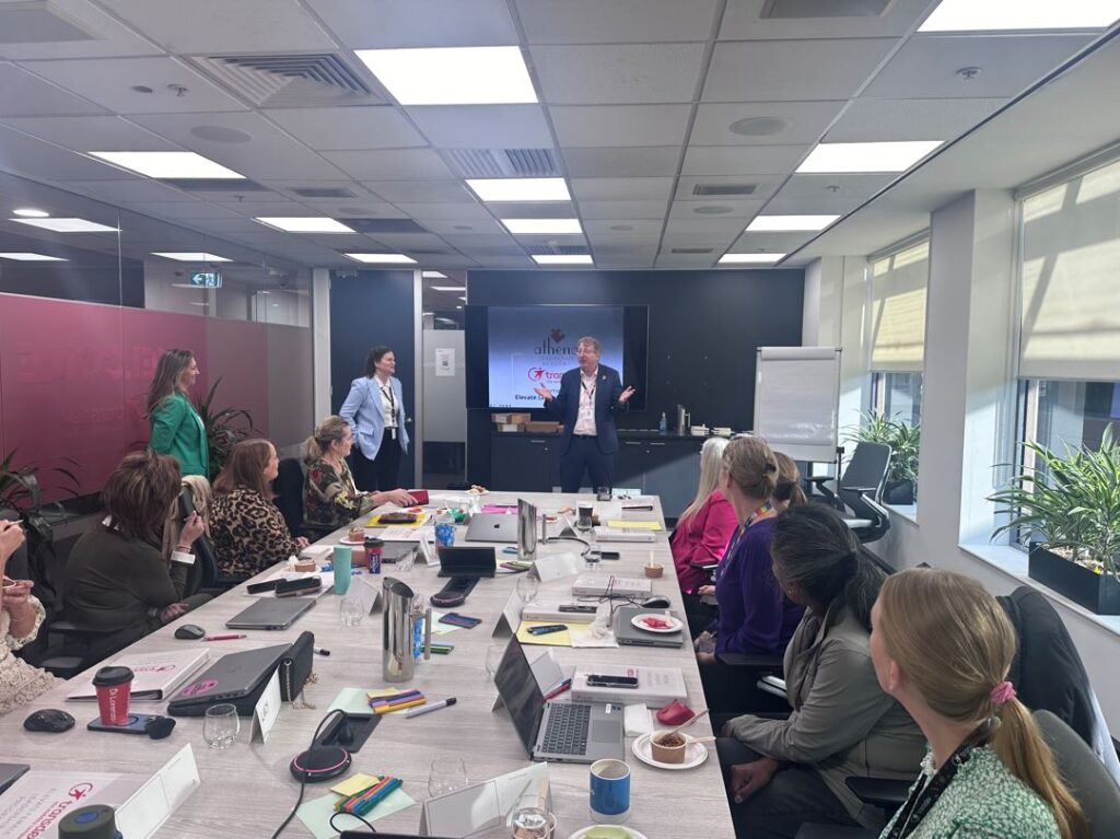 A table full of female Transdev employees sit around a table watching a man and a woman give a presentation.